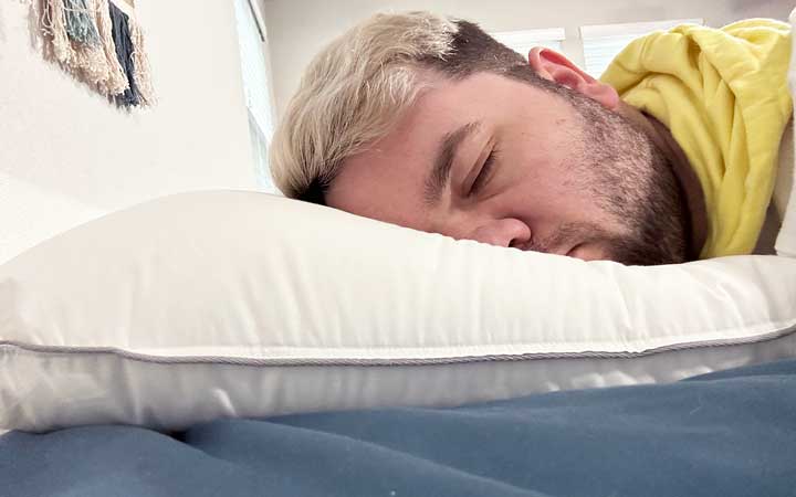 An image of a man resting on his stomach using the Tuft & Needle Down Alternative pillow.