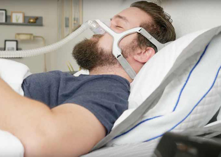 A man sleeps on his back, wearing a CPAP mask