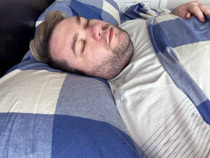 A man rests on his back using the Brooklinen Flannel Sheets.