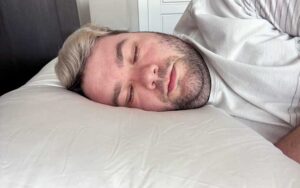 An image of a man sleeping on his side while using the Cozy Earth Silk Pillow.