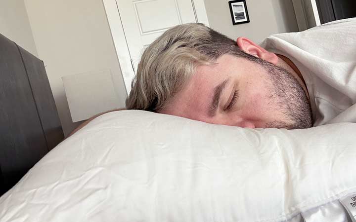 An image of a man sleeping on his stomach while using the Cozy Earth Silk Pillow.