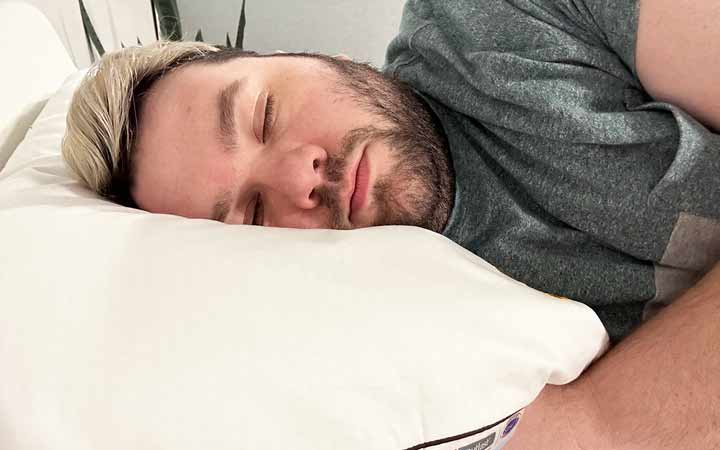 An image of a man sleeping on his side while using the Nolah Airfiber Pillow.