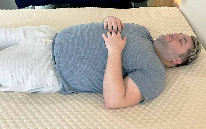 A man rests on his back while on top of the Nolah Mattress Topper.