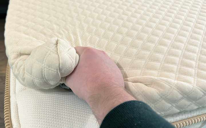 A hand squeezes the Nolah Mattress Topper.