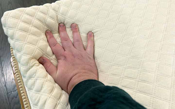 A hand presses into the Nolah Mattress Topper.