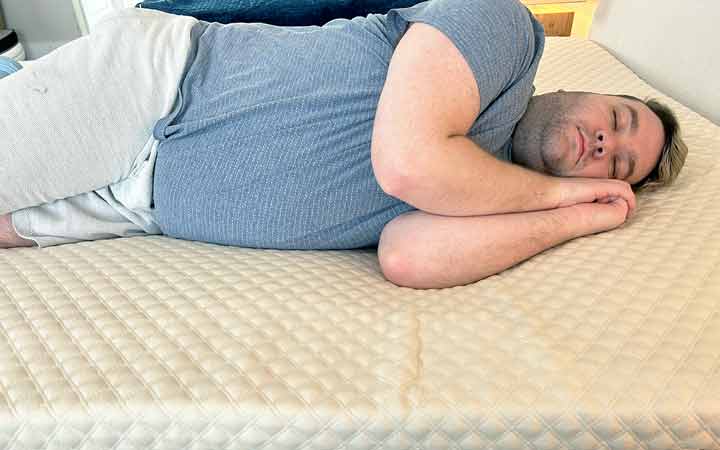A man rests on his side while on top of the Nolah Mattress Topper.