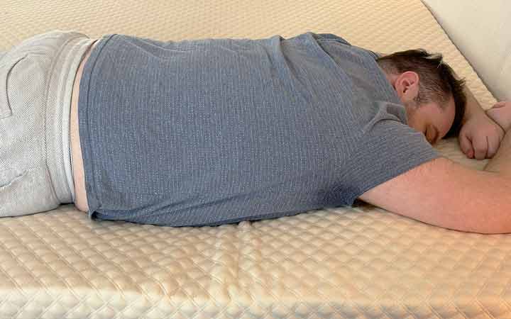 A man rests on his stomach while using the Nolah Mattress Topper.