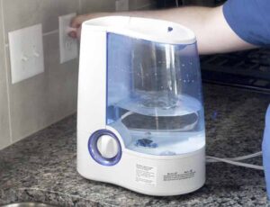 An image of a man plugging in the Vicks Warm Mist humidifier.