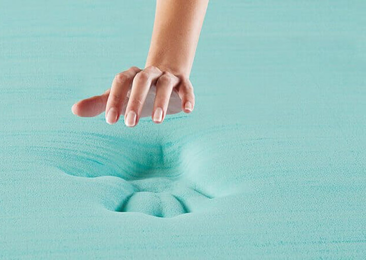 A woman's hand rises above a handprint in memory foam