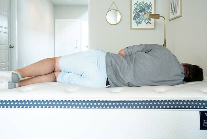 A man sleeps on his side on the WinkBed Plus