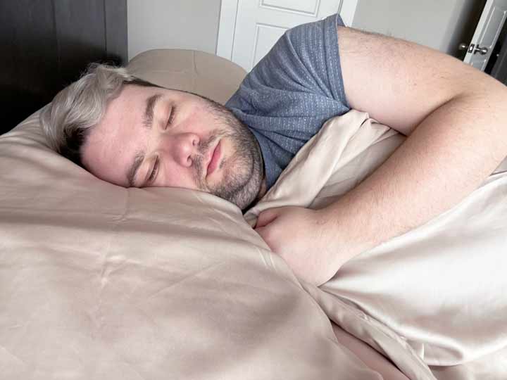 A man sleeps on his side with the Ettitude Bamboo Sheets pulled tight.