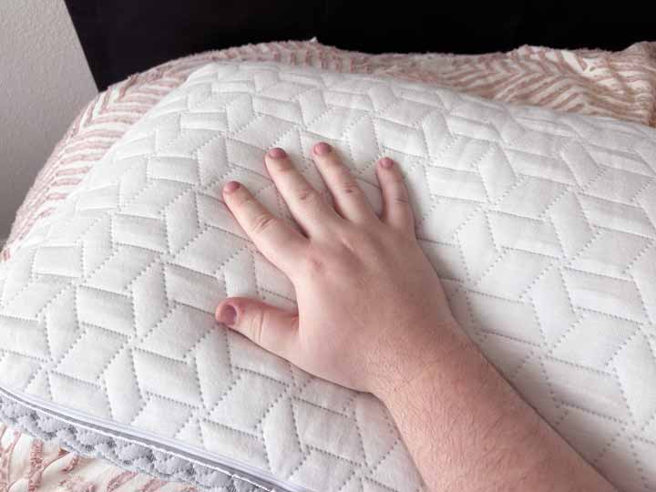 A hand rubs the cover of the Luxome Layr pillow.