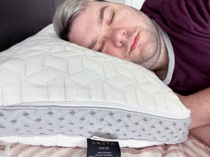 A man sleeps on his side while using the Luxome Layr pillow.