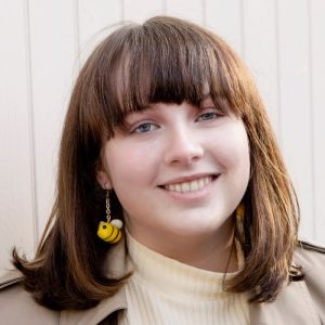 Livvi wearing felted bumblebee earrings and smiling.