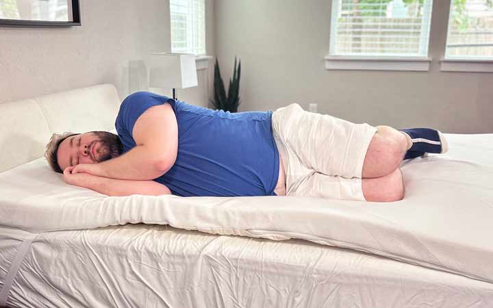 A man rests on his side while on top of the TEMPUR-Adapt mattress topper.