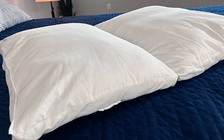 An image of the Purple TwinCloud pillow unzipped on a bed.
