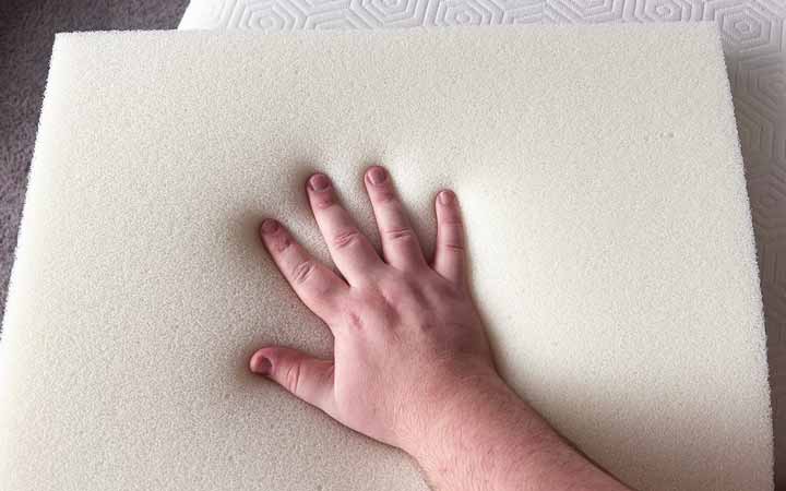 A hand presses on a piece of foam.