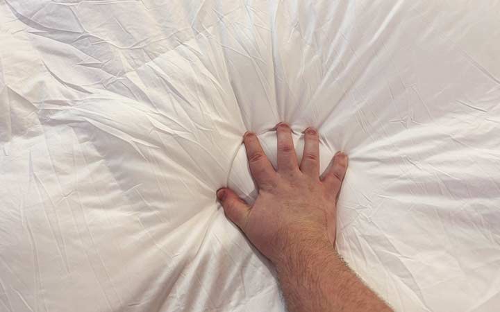 A hand squeezes the Luxome ClimaSense Comforter to show how fluffy it is.