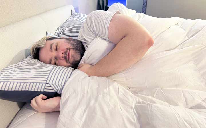 A man rests on his side while covered with the Luxome ClimaSense Comfroter.