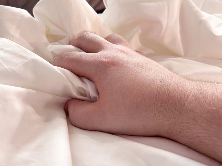 A hand squeezes the Nest Silk Cloud Comforter to show the fluff.