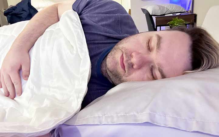 A man sleeps on his side while using the Nolah Bamboo comforter.