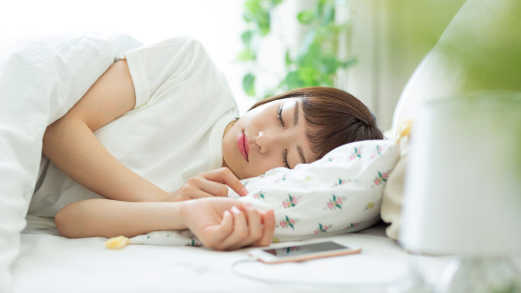 Woman sleeping with phone charging in bed