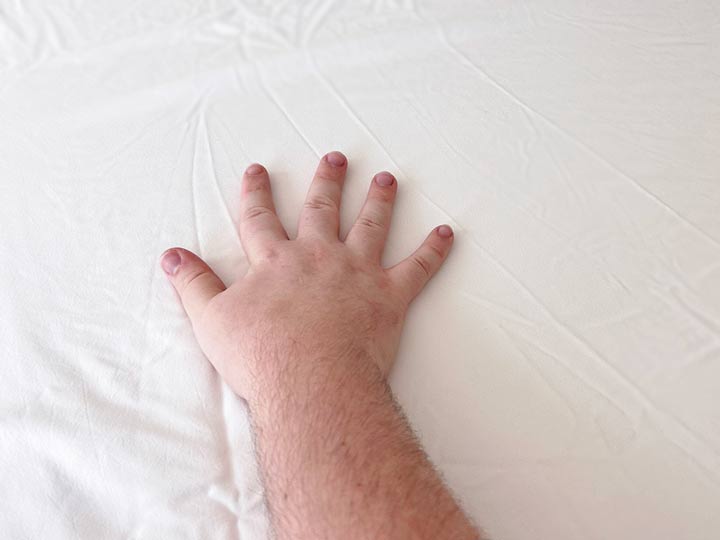 A hand brushes across the Plushbeds Bamboo Sheets.