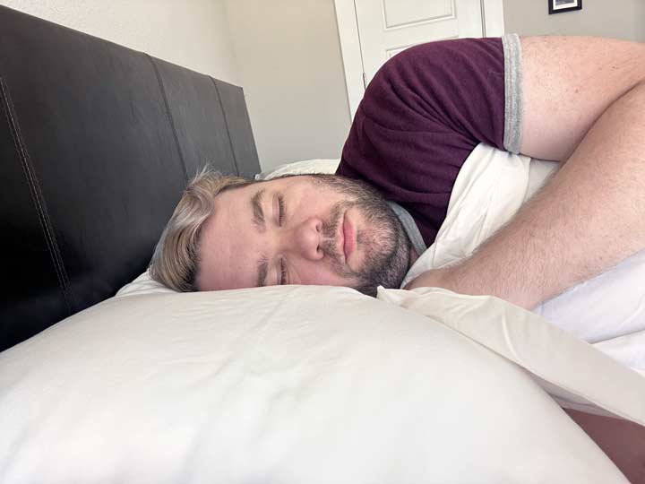 An image of a man sleeping on his side while using the Plushbeds Bamboo Sheets.