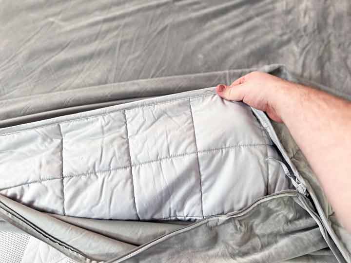 A hand pulls out the weighted insert of the Puffy Weighted Blanket.