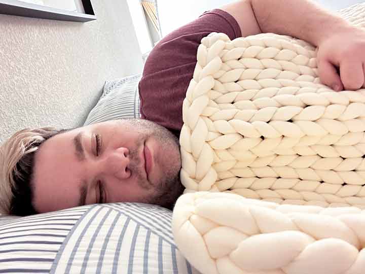 A man sleeps with the Brooklyn Bedding Weighted Blanket.