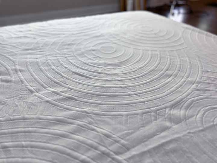 A close up image of the TEMPUR-Protect mattress cover's top layer, showing off a circular pattern in the polyester fabric.