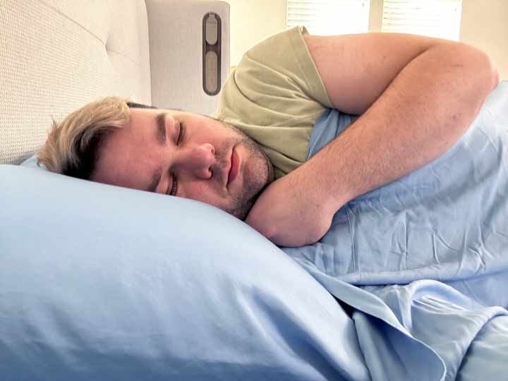 An image of a man sleeping on his side with the blue Sweet Zzz Bamboo Sheets.