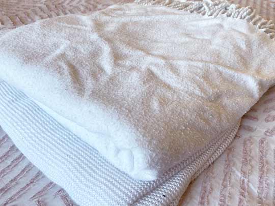 An image of two blankets or coverlets stacked on top of one another.