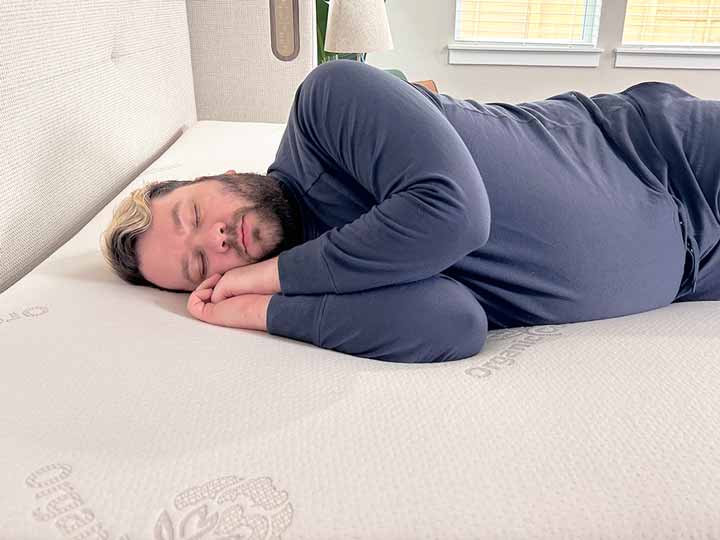 An image of a man resting on his side while on top of the Brooklyn Bedding Latex Topper.