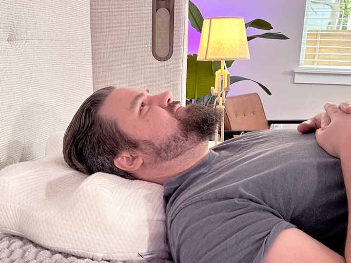 A man rests on his back while using the Lundberg CPAP pillow.