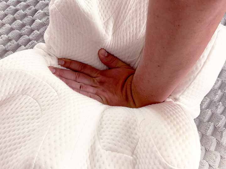 A hand presses firmly into the Lundberg CPAP pillow to show its firmness.