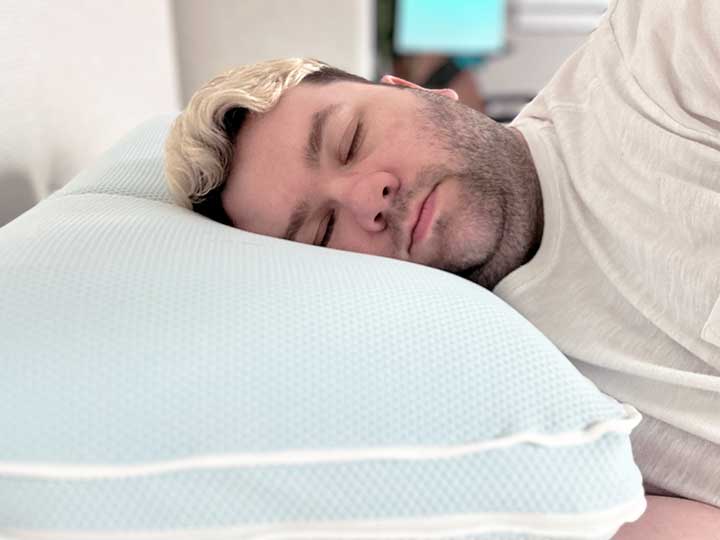An image of a man sleeping on his side while resting his head on the TEMPUR-Cloud Cooling Pro pillow.