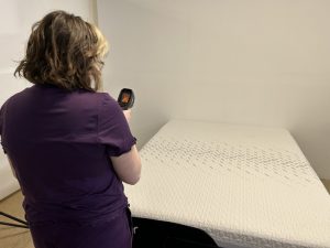 A woman aims a temperature gun at the Nectar Classic mattress