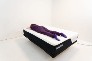 A woman rests on her stomach on the Nectar Classic mattress