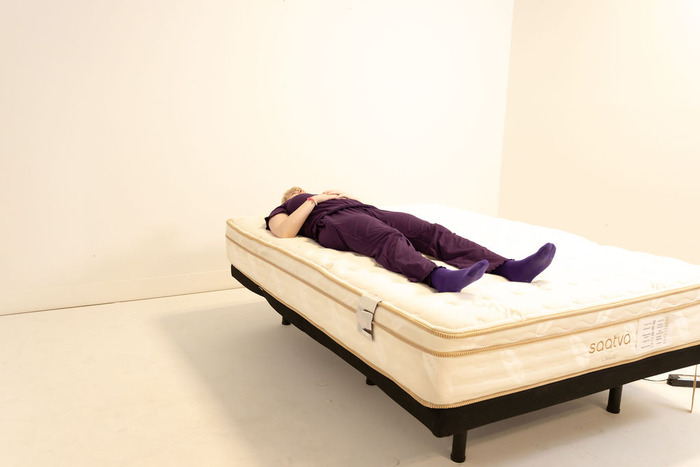 A woman resting on her back on the Saatva Classic