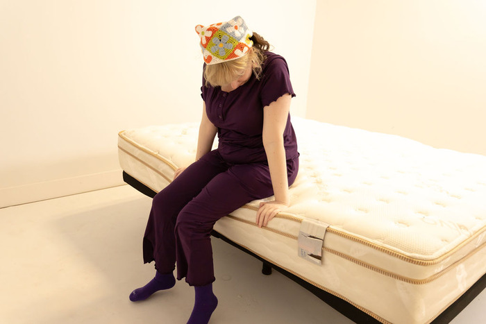 A woman sitting on the side of the Saatva Classic