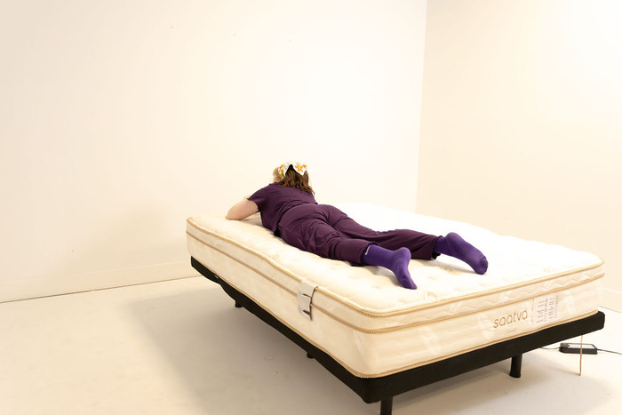 A woman resting on her stomach on the Saatva Classic