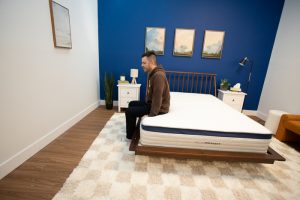 A man sitting on the edge of the Helix Midnight mattress