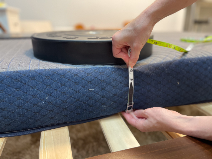 Measuring the edge support of the Brooklyn Bedding Kids mattress by seeing how much the side sinks when a weight plate is placed near the edge