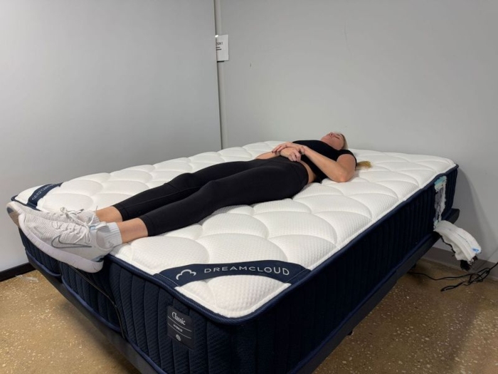 A person is shown back-sleeping on a DreamCloud Classic Hybrid mattress.