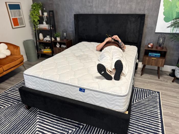 A woman lying on her back on the DLX Classic Two-Sided Mattress