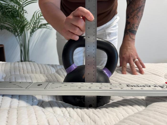 A kettlebell on top of the DLX Classic Two-Sided Mattress, with rulers measuring the sinkage on the mattress surface