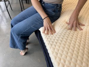 Our tester sits along the edge of a Nolah Mattress Topper