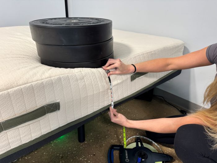 A woman measures sinkage with 3 weights on the Avocado Eco Organic Mattress