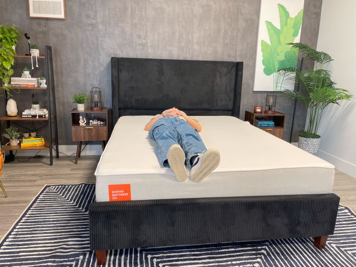 A woman lays on her back on the Boring AF mattress